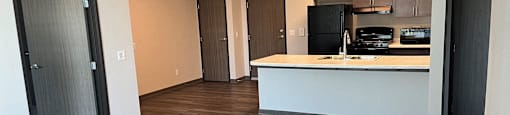 an empty living room with a kitchen and a door to a closet