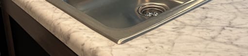 a stainless steel sink in a marble counter top in a kitchen