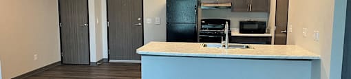 a kitchen and living room with a blue island and a black refrigerator