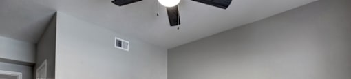 a bedroom with gray walls and a ceiling fan