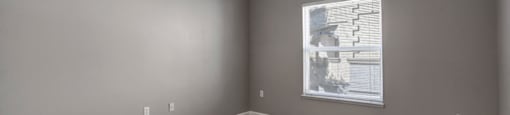 an empty room with a ceiling fan and a window