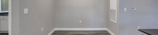 a kitchen and living room with grey walls and a wooden floor