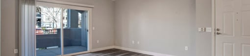an empty living room with a sliding glass door and a ceiling fan