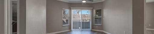 a living room with a ceiling fan and a door to a balcony