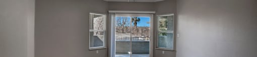 a living room with a ceiling fan and a door to a balcony