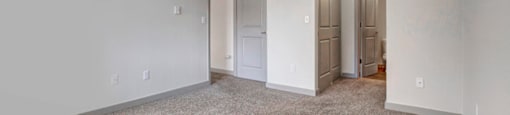a bedroom with white walls and a carpeted floor