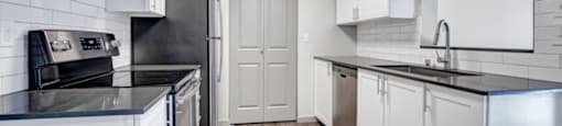 a kitchen with white cabinets and black counter tops
