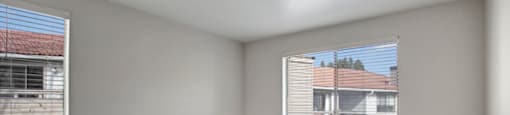 a bedroom with two windows and a carpeted floor