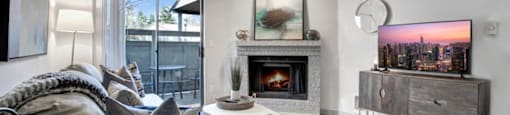 a living room with a fireplace and a sliding glass door to a balcony