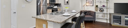 A kitchen with a granite countertop and a bar stool.