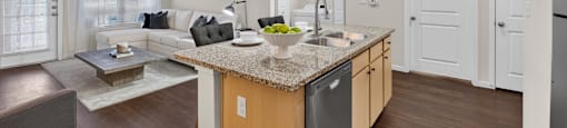 A modern kitchen with a granite countertop and a dining area with a table and chairs.
