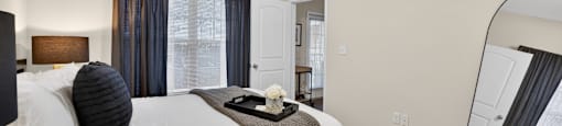 A bedroom with a bed, a ceiling fan, and a mirror.