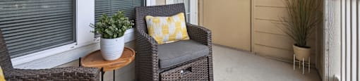 A patio with a chair, table, and potted plant.