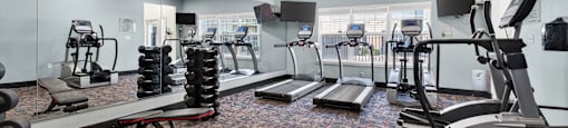 A gym with a variety of equipment including treadmills, weights, and exercise machines.