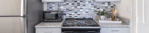 a small kitchen with white cabinets and a stainless steel refrigerator