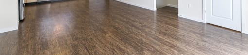 an empty living room and kitchen with wood floors