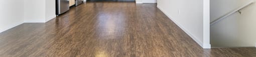 an empty living room and kitchen with wood floors and white walls