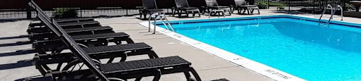 a swimming pool with chaise lounge chairs and trees in the background