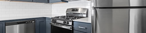 A modern kitchen with dark blue cabinets and stainless steel appliances.