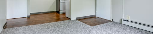 A room with a carpeted floor, a white door, and a white wall.