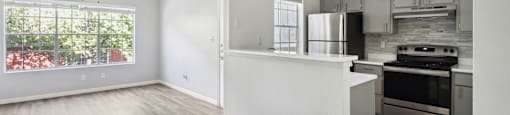 an empty apartment with a kitchen and a large window