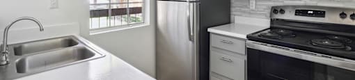 an empty kitchen with stainless steel appliances and white cabinets