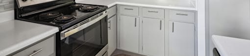 an empty kitchen with white cabinets and a stove