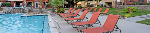 a row of red lounge chairs next to a swimming pool