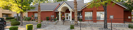 the front of a red building with a parking lot and palm trees
