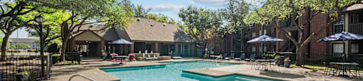 A pool surrounded by trees and a building in the background.