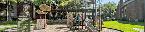 A playground with a slide, swings, and a sign.