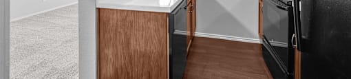 A kitchen with a black refrigerator and wooden cabinets.