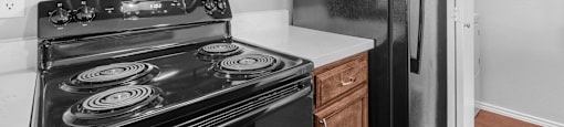 A black stove and microwave in a kitchen with wooden cabinets.