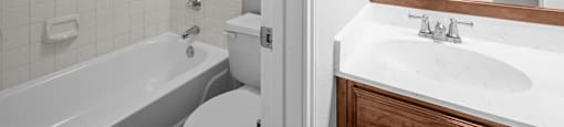 A white bathroom with a white toilet, white sink, and a white bathtub.
