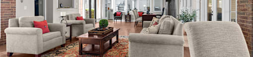 A living room with a rug and a ceiling fan.