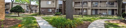 pathway leading to an apartment building with trees and grass