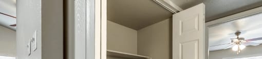 A white door is open to a room with a carpeted floor and a wooden floor leading to a closet.