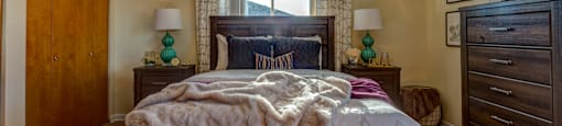 A bedroom with a bed, dresser, and ceiling fan.