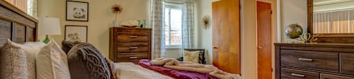 A bedroom with a bed, dresser, and mirror.