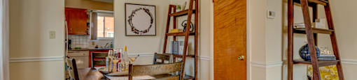 A dining room with a table and chairs and a ladder.