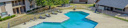 A large swimming pool surrounded by a fence and trees.