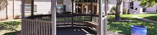 A wooden gazebo with a blue planter to the right.
