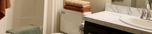 A bathroom with a white sink, toilet, and shower curtain.