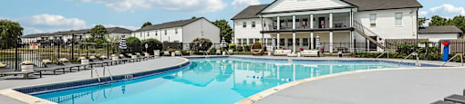 A large swimming pool in front of a white house.
