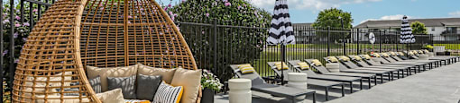 A wicker chair is in the foreground of a patio area.