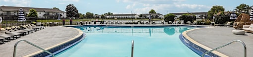 A large outdoor swimming pool with a clear blue sky and some clouds in the background.