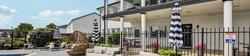 A patio area with a white sofa and a black and white striped umbrella.