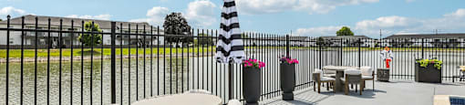 A black and white striped lighthouse is in the middle of a patio with a table and chairs.