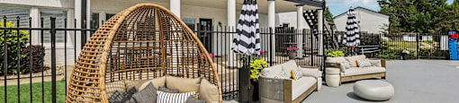 A wicker chair with cushions is in the foreground of a patio area.