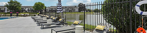 A sunny day at the poolside with lounge chairs and a lifebuoy.